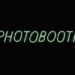 a neon sign that reads photo booth on a dark background